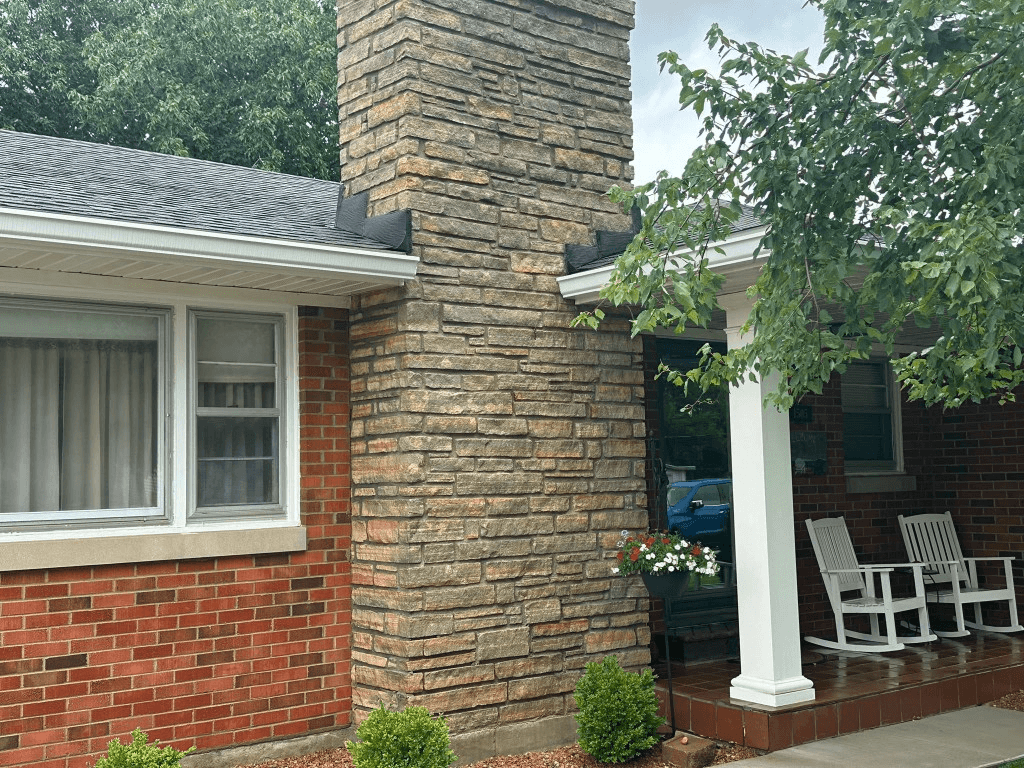 Red brick home with a stone chimney and clean white trim